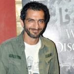 عمرو واكد إلى جانب ملصق لفيلم 'الشتا اللي فات'
