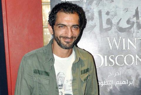 عمرو واكد إلى جانب ملصق لفيلم 'الشتا اللي فات'
